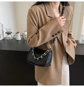 Détail du sac à bandoulière noir texture litchi avec chaîne dorée et fine lanière