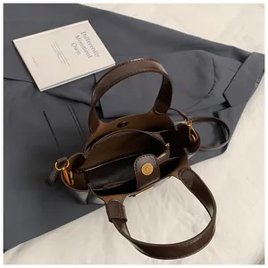 Detail view of the brown leather bucket bag interior with zipper compartment and magnetic buckle