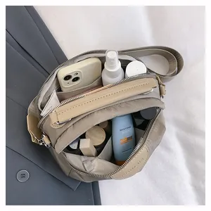 Détail macro du sac à bandoulière en nylon beige montrant les compartiments et la capacité