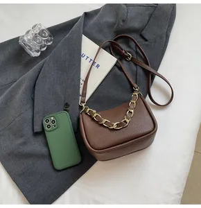 Vue détaillée du cuir marron foncé et de la chaîne dorée sur le sac à main chic