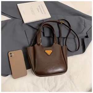 Detail of dark brown leather bucket bag with triangle logo, shoulder strap and top handle