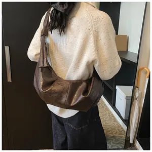 Detail of a large coffee brown crescent bag with pleated soft leather texture on a model