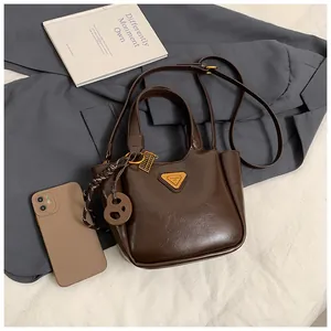 Close-up of a dark brown bucket bag with gold triangle logo and stylish side charms