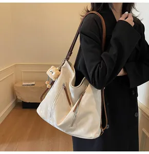 Detail of cream leather tote bag featuring side zipper pocket and plush bear charm