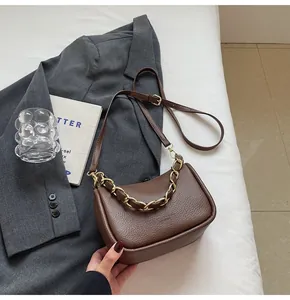 Détail du sac en cuir litchi marron foncé avec une poignée en chaîne dorée épaisse