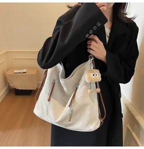 Detail view of cream white leather hobo bag with contrast brown straps and plush charm