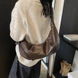 Large dark brown crescent bag with vintage pleated leather texture and knot shoulder strap