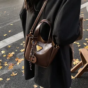 Chic dark brown glossy leather bucket bag with gold triangle plaque for autumn winter