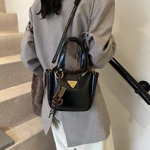 Glossy black bucket bag with golden triangle logo and silk scarf on a staircase