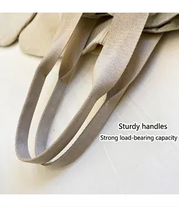 Detail showing reinforced nylon handle and high-density stitching on beige tote bag