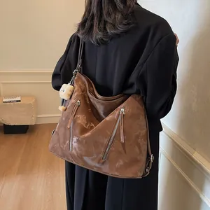 Vintage brown leather tote bag with decorative zippers and bear charm shown on model