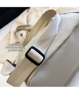 Detail of adjustable strap on a minimalist off-white backpack with matte plastic buckle