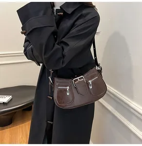 Detail der dunkelbraunen Leder-Achseltasche mit dekorativen Schnallen und Metall-Zippern