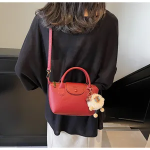 Detail of red dumpling handbag with litchi texture and a cute white sheep charm