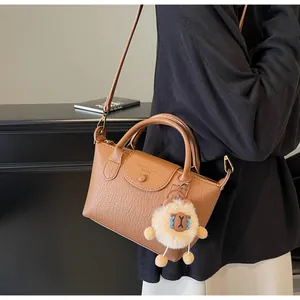 Detail of brown textured leather dumpling bag with a cute white sheep charm