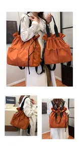 Detail view of orange drawstring tote bags in two sizes with black contrast straps
