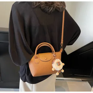 Brown lychee texture dumpling bag with top handles and cute sheep pendant on model