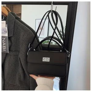 Detail of black crossbody bag with mixed leather textures and silver twist lock closure