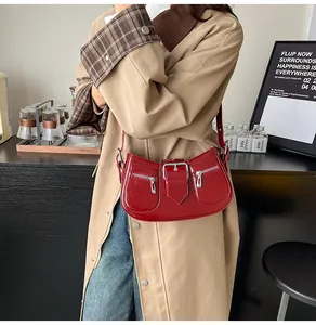 Detailansicht der roten glänzenden Achseltasche mit Silberschnallen und Reißverschlüssen