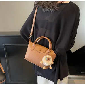 Detailed shot of brown textured leather crossbody bag with a white plush sheep charm