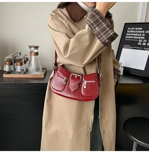 Detailansicht einer burgunderroten Lackledertasche mit Metallschnalle und Reißverschlüssen