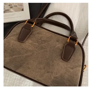 Detail of vintage textured fabric and golden hardware on a brown Boston handbag