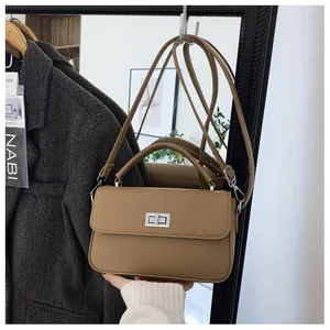 Detailed view of khaki leather handbag with silver turn-lock and adjustable strap