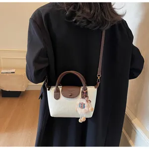 Detail of a two-tone Boston bag with pebbled leather texture and cute sheep charm