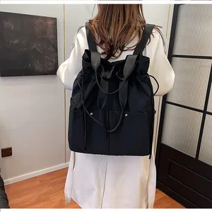 Detail of black cloud drawstring backpack on a model showing large capacity and nylon texture