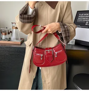 Detail der roten Lackleder-Hobo-Tasche mit Silberschnallen auf beigefarbenem Mantel