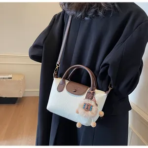Close-up of beige pleated texture handbag with contrast brown straps and plush lion charm