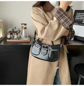 Makro-Detail der glänzend schwarzen PU-Leder-Schultertasche mit Schnallen und Zippern