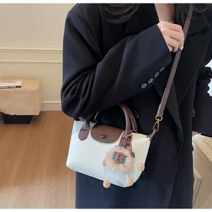 Detailed view of bicolor crossbody dumpling bag with white lychee grain leather and lion charm
