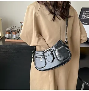 Detailansicht einer glänzenden schwarzen Ledertasche mit silbernen Reißverschlüssen und Metall