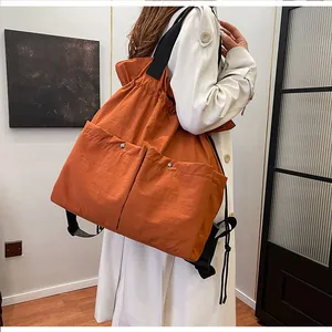 Detail of orange drawstring backpack with dual front pockets and glossy nylon texture