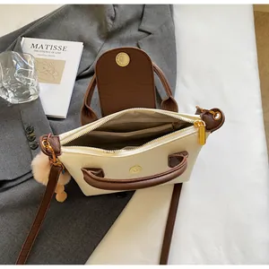 Top view of cream and brown crossbody bag showing zipper closure and internal pockets