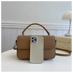 Detail of brown leather handbag with lychee texture and phone for size reference