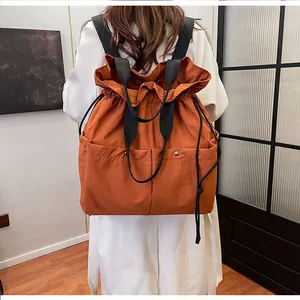 Rear view of model wearing a bright orange cloud backpack with drawstring closure