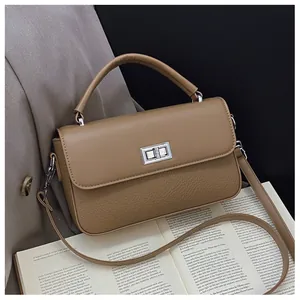 Detail shot of khaki lychee texture leather bag with silver twist lock on an open book