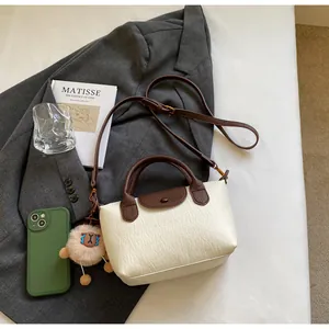 Close-up of cream textured leather tote bag with brown flap and sheep charm detail