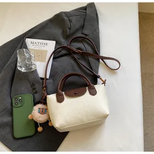 Detail of cream lychee texture bag with dark brown straps and a plush sheep charm