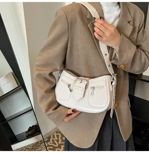 Detail der cremefarbenen Lackleder-Achseltasche mit Gürtelschnallen und Seitentaschen