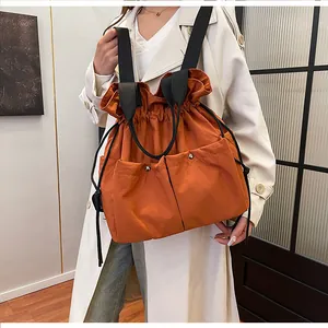 Close-up of burnt orange drawstring tote bag with large utility pockets and metal snaps