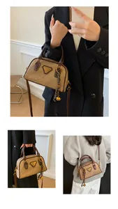 Close-up of vintage khaki Boston bag with brown handles and a bell decorative pendant