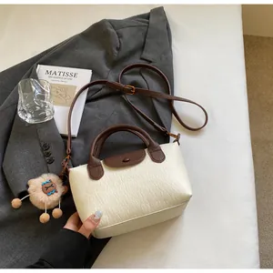 Detail view of contrast leather handbag with adjustable strap and plush bear charm