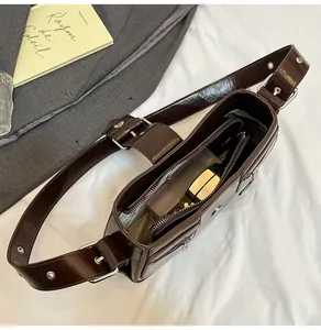 Innendetail der dunkelbraunen glänzenden Tasche mit Reißverschlussfächern und breitem Gurt
