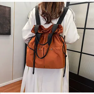 Close-up of bright orange drawstring backpack showing waterproof nylon and side pockets
