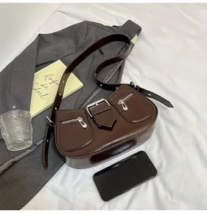 Detail der dunkelbraunen Glanzledertasche mit Schnallen und Reißverschlusstaschen