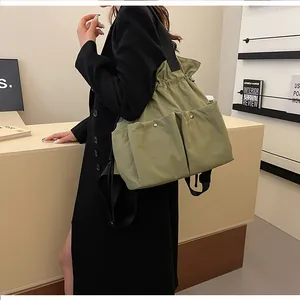 Detail of drawstring green nylon tote with large front pockets and black shoulder strap
