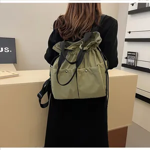 Olive green drawstring backpack shown on a model with functional side flap pockets